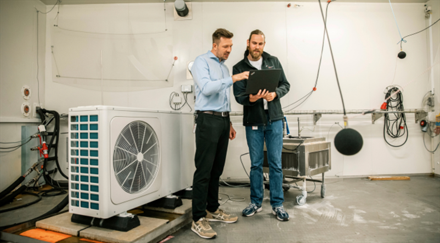 To specialister gennemgår en varmepumpe i et testlaboratorium i forbindelse med performance-test og Ecodesign-overholdelse.